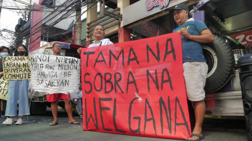 PUV drivers and operators in their picket line during a strike in Manila. A red banner reads, "Tama na, Sobra na, Welga na!"